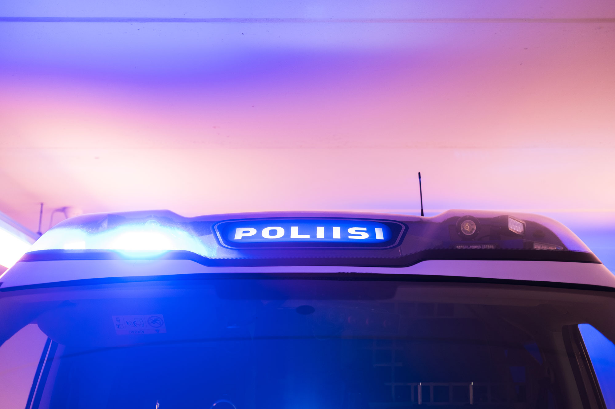 The light bar of a police car with the blue light pictured against the sky.