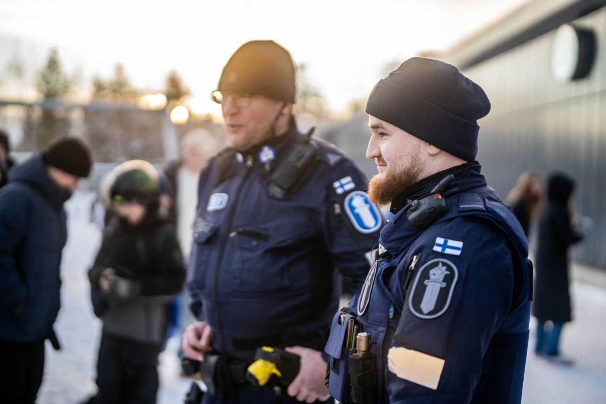 Kaksi poliisia koulun pihalla juttelemassa koululaisten kanssa.