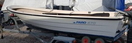 Kuvassa venetrailerin päällä oleva vaalea vene, johon on kiinnitetty perämoottori