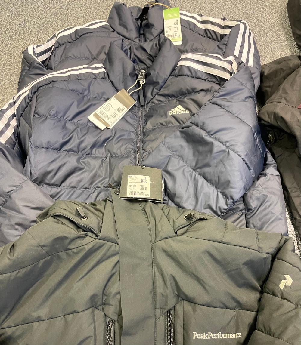 Vaatteita lattialla. Viisi takkia, kahdet housut sekä teknisiä paitoja. 