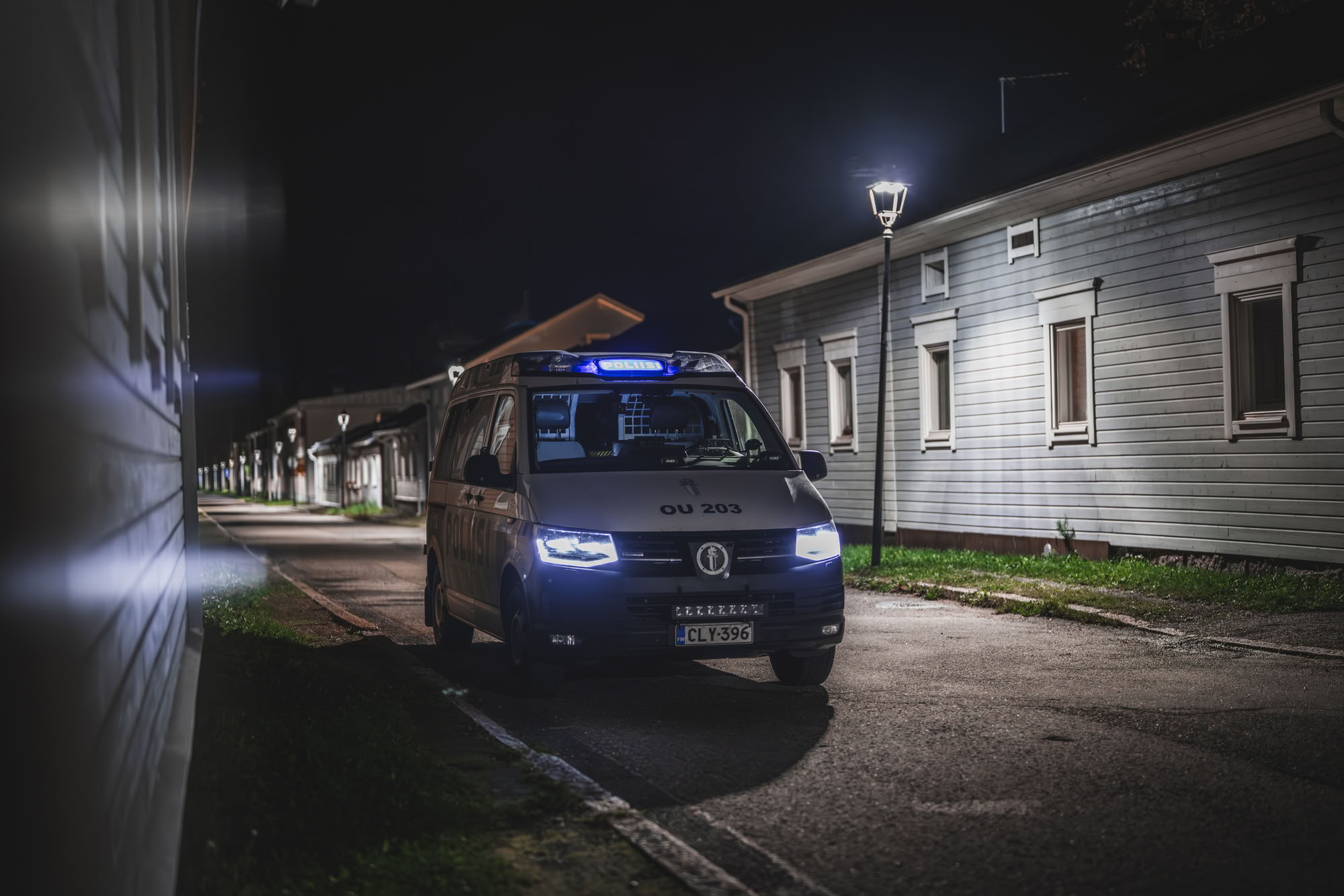 En polisbil av modellen Volkswagen Transporter i gamla Brahestad på hösten. Gatubelysning lyser upp den mörka miljön.