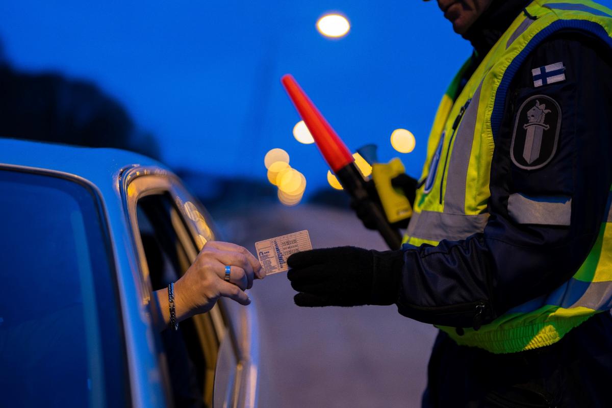 Henkilöauton kuljettaja ojentaa poliisille ajokorttia. Maisema on aamuhämärän sininen. Poliisilla on ylllään keltainen huomioliivi ja kädessään huomiovalo ja alkometri. Henkilöauton kuljettajasta näkyy vain käsi sivuikkunasta.
