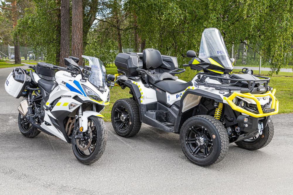 En polismotorcykel och polisens fyrhjuling står parkerade bredvid varandra.