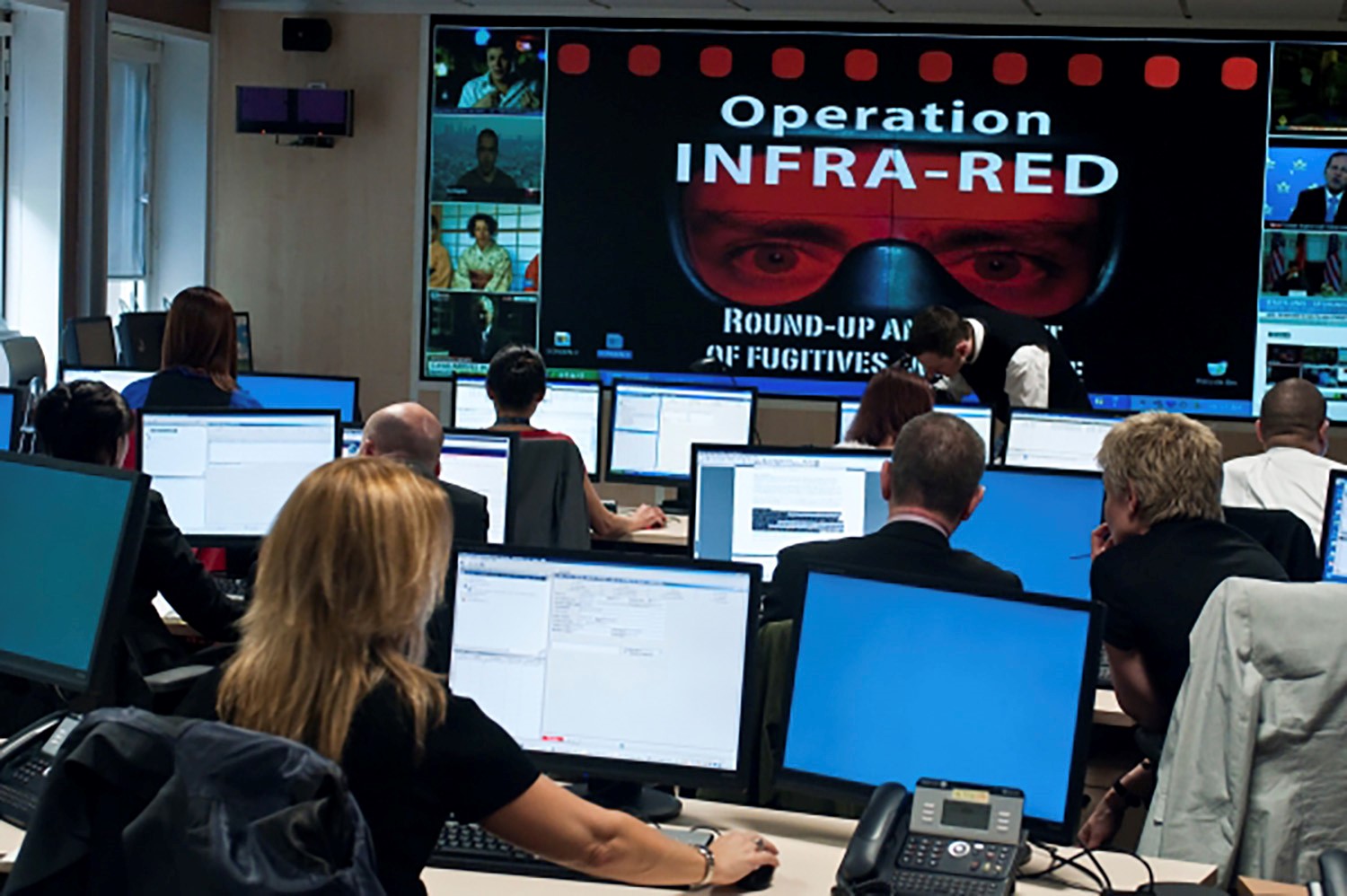 Ihmisiä luokkahuoneessa tietokoneiden äärellä. Edessä isolla ruudulla teksti Operation Infra-Red.
