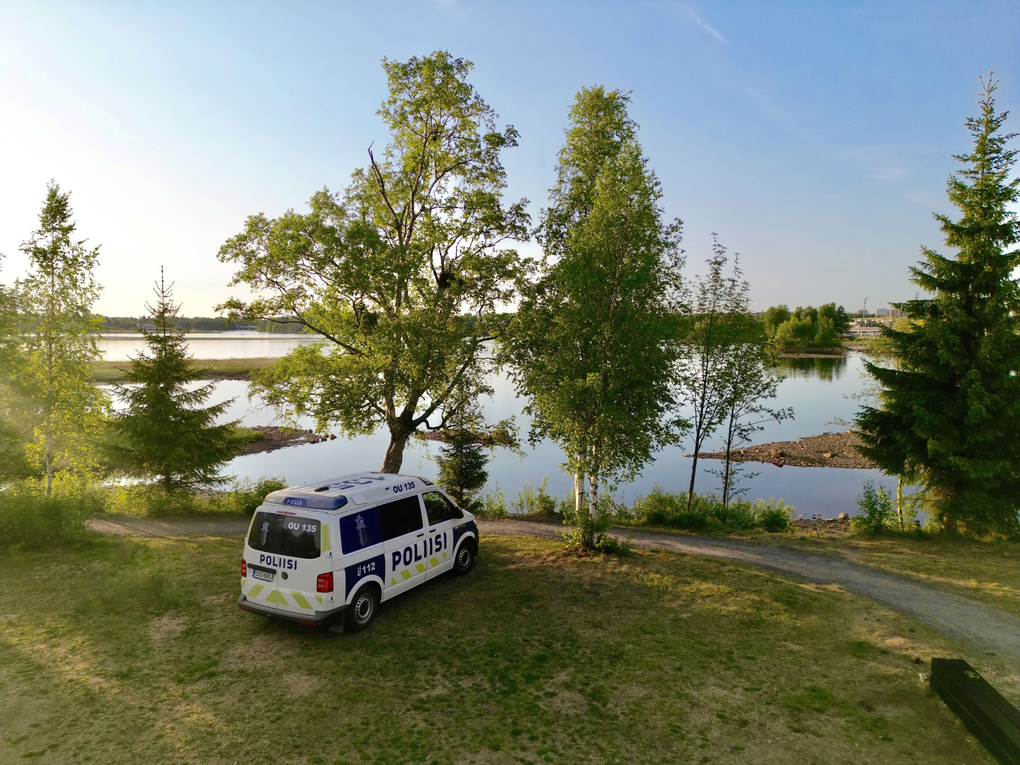 En polisbil i Kiikeli i Uleåborg på sommaren. Björkar och vatten syns i bakgrunden. Bilden är tagen från luften.