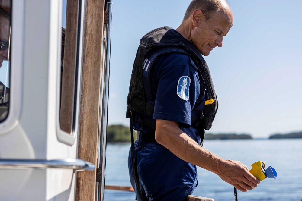 Venepoliisi seisoo veneen kannella alkometri kädessään. 