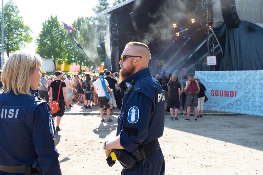 Kaksi poliisia valvomassa turvallisuutta festivaaleilla. Taustalla festivaalivieraita lavan edessä.