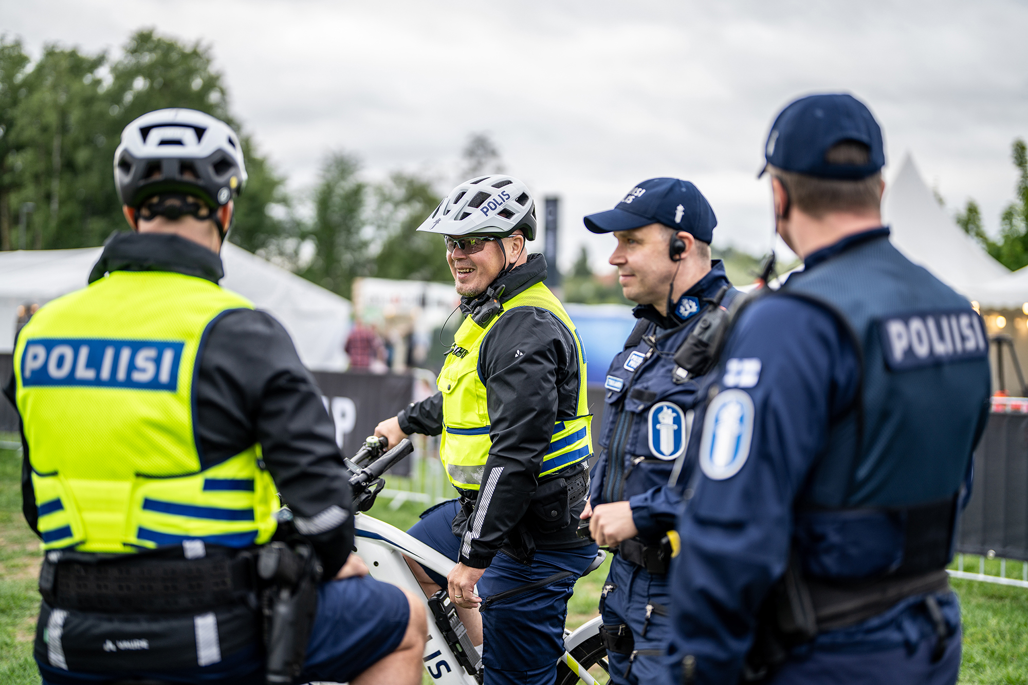 Bicycle police officers and a patrol unit move through a festival area in Oulu during the summer.