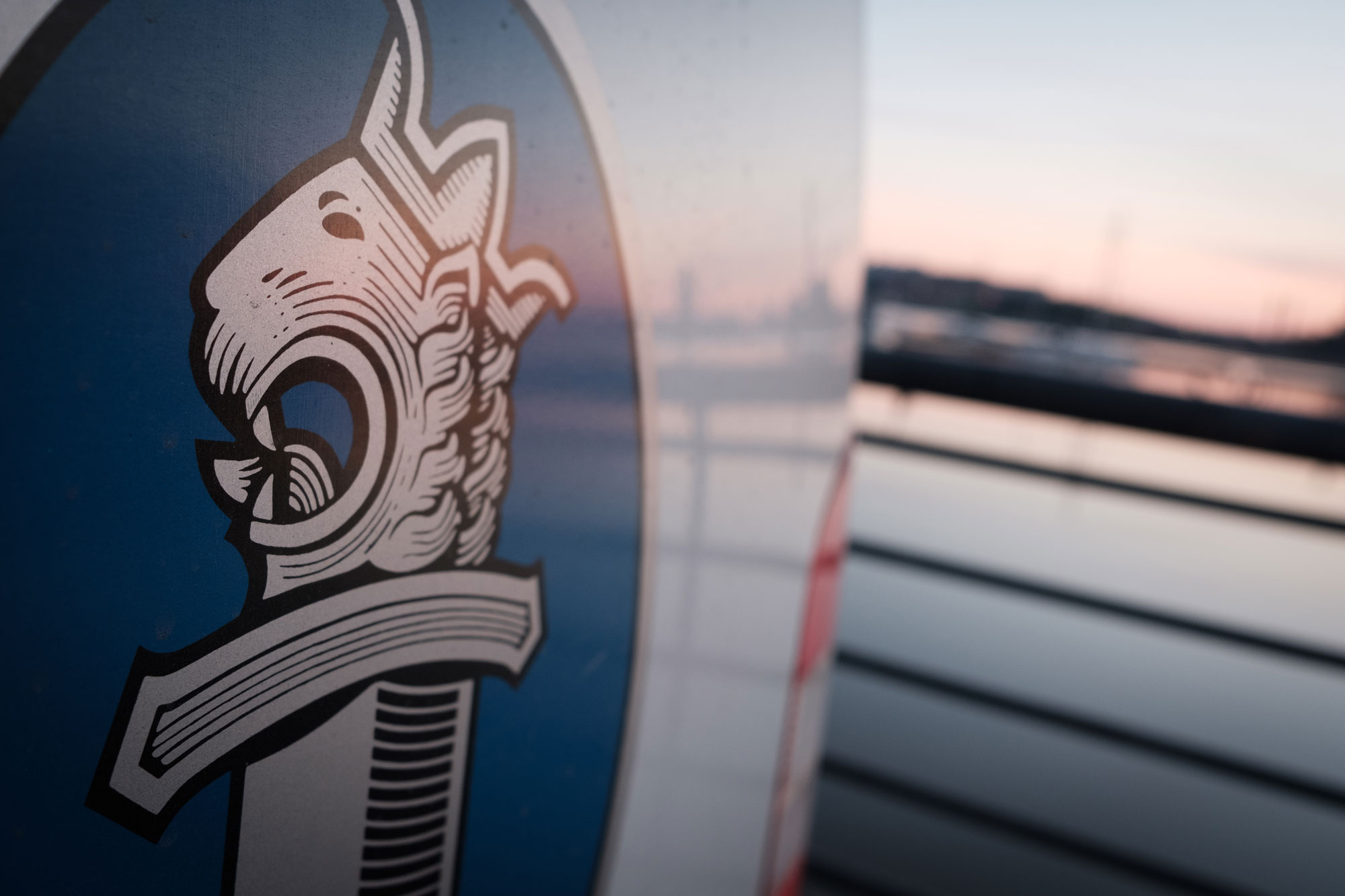 The sword-and-lion emblem on the side of a police car in the foreground with the sea in the background.