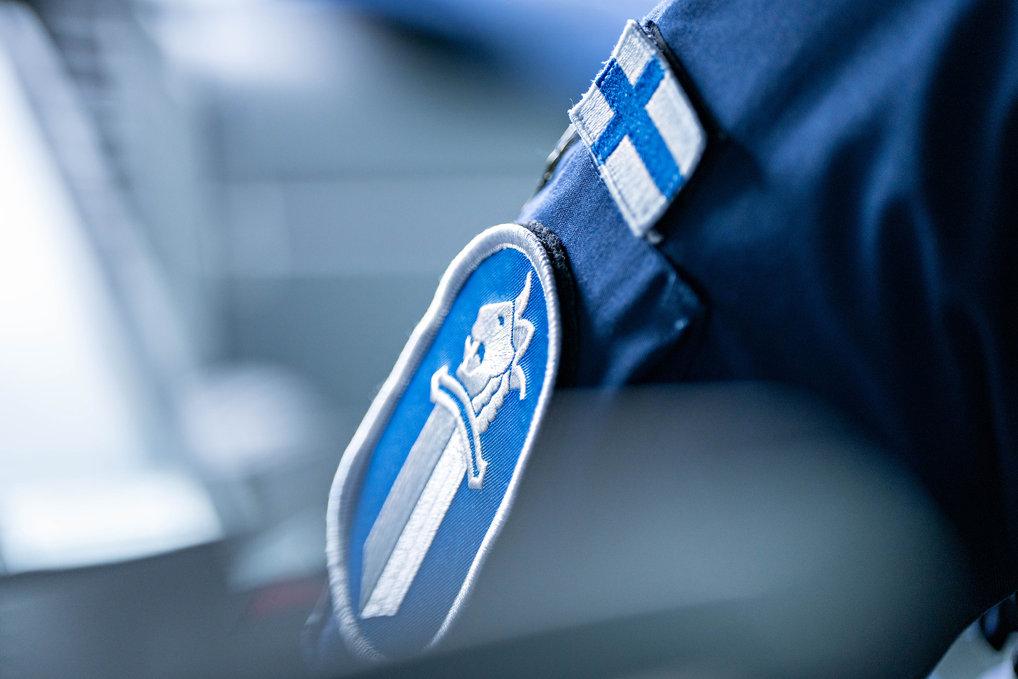 Poliisin haalarin hihassa näkyy miekkatunnus ja Suomen lippu lähikuvassa.