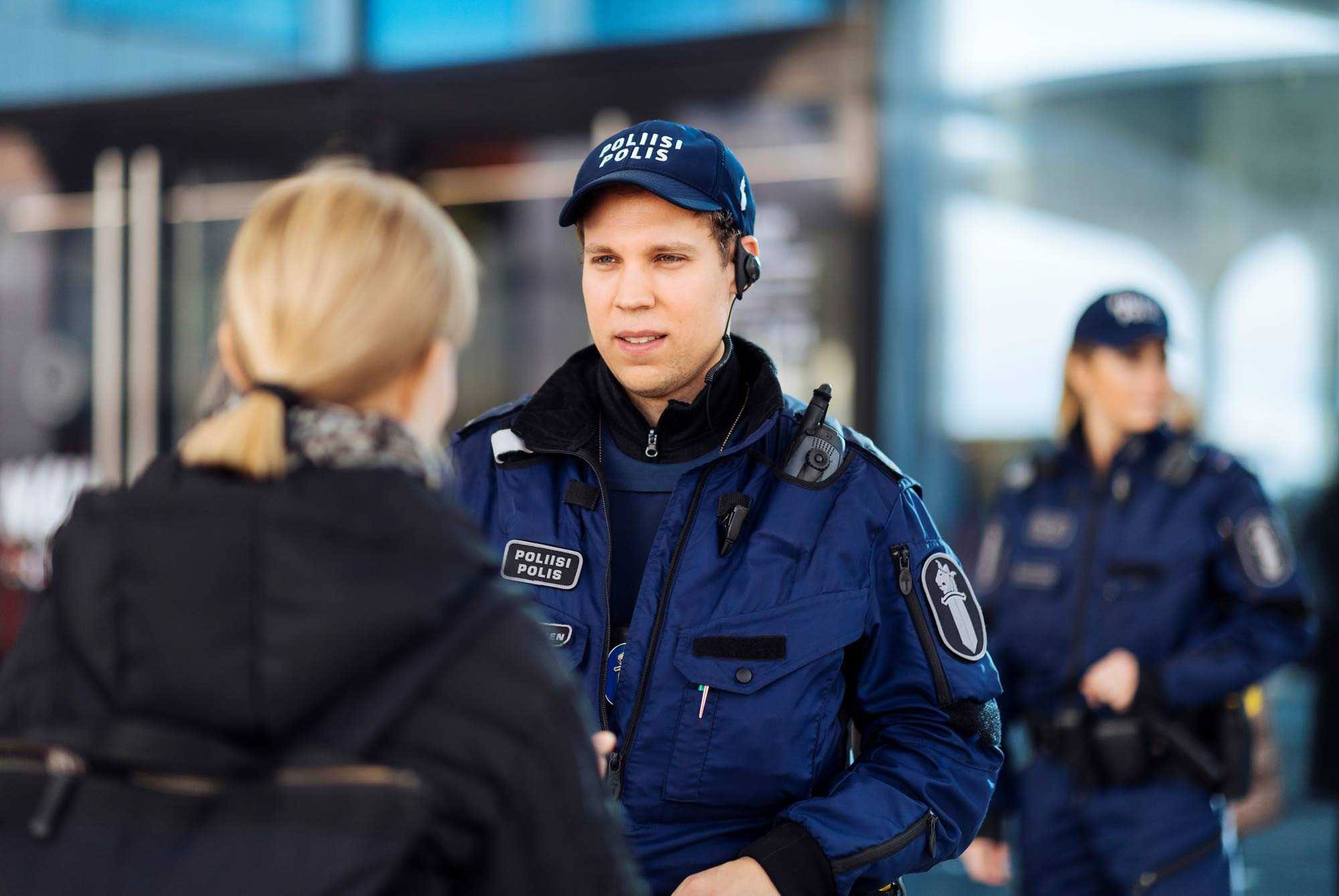 Poliisi keskustelee asiakkaan kanssa etualalla, taustalla partion toinen konstaapeli.