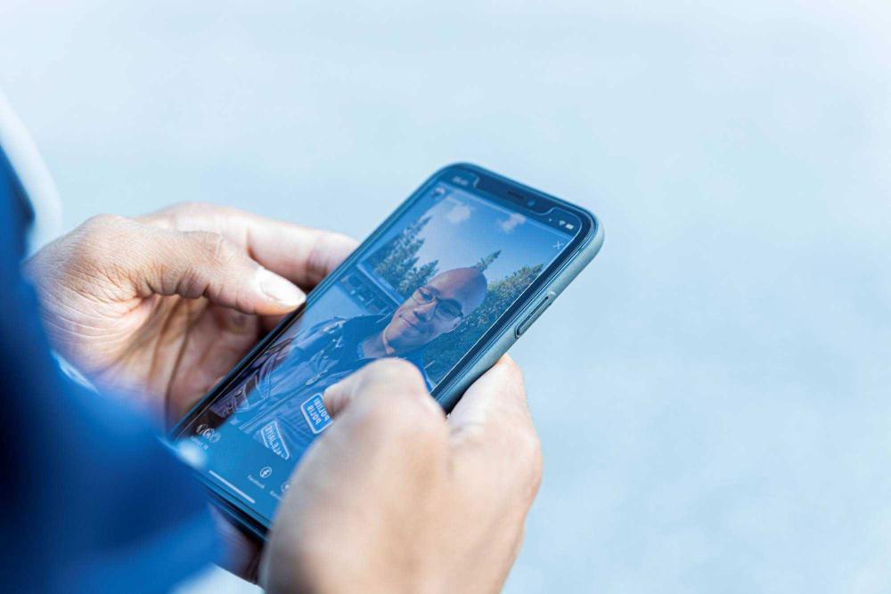 En smarttelefon i en polis hand. På skärmen ett porträtt av konstapeln.