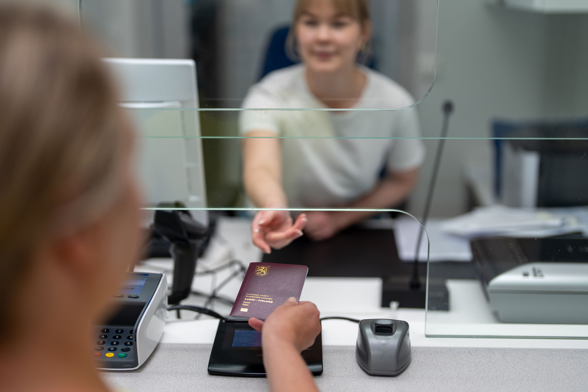 Lupasihteeri ojentaa passia asiakkaalle.