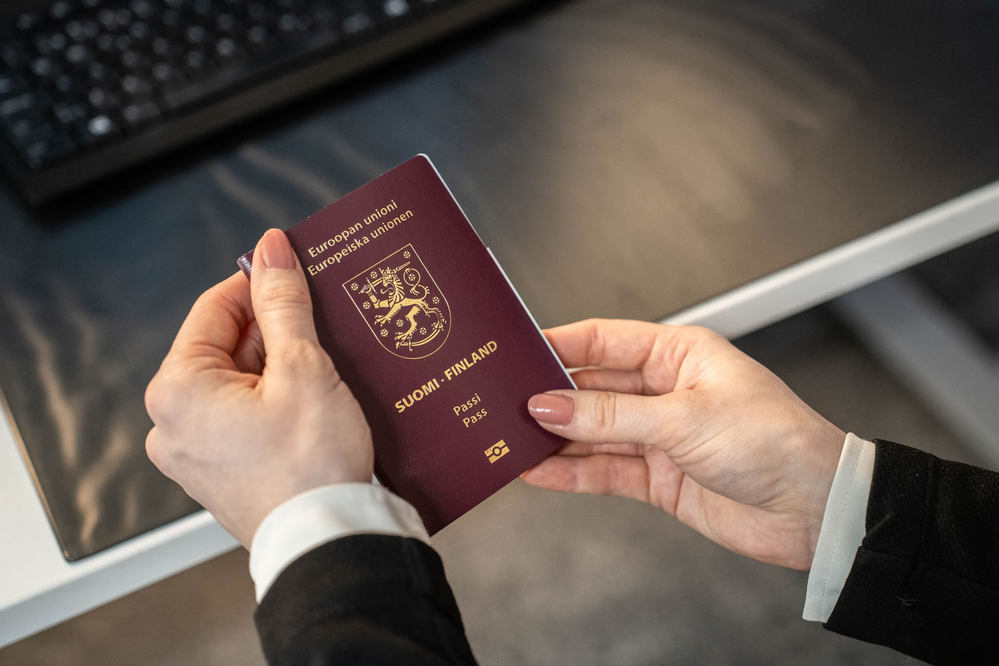 An older model passport is held in the hand of a permit specialist. Illustrative image.