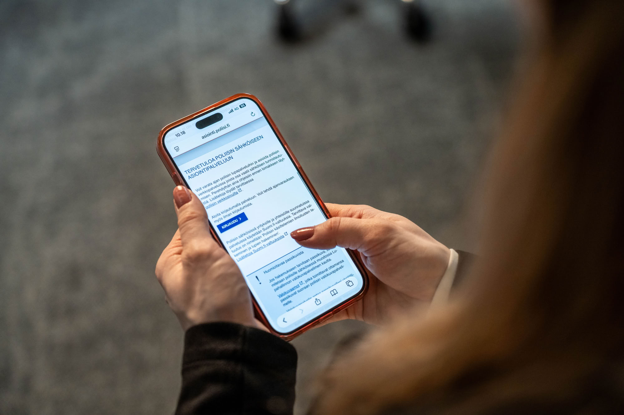 A woman holds a mobile phone displaying the police’s electronic service portal. Illustrative image.