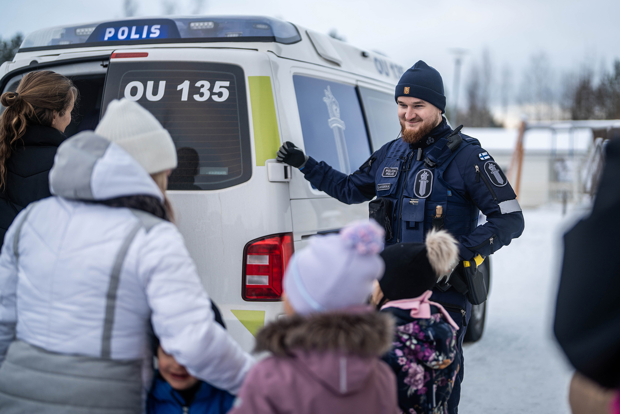 Poliisi esittelee lapselle poliisiauton laitteita.