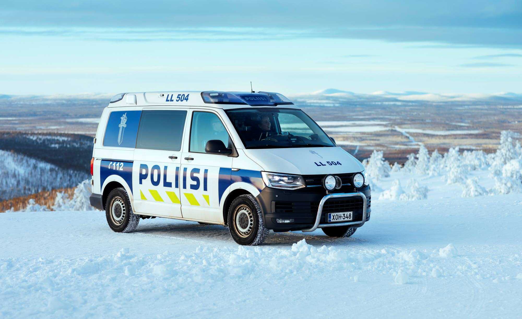 A police car in Lapland on top of a snowy mountain. More mountains can be seen in the background.