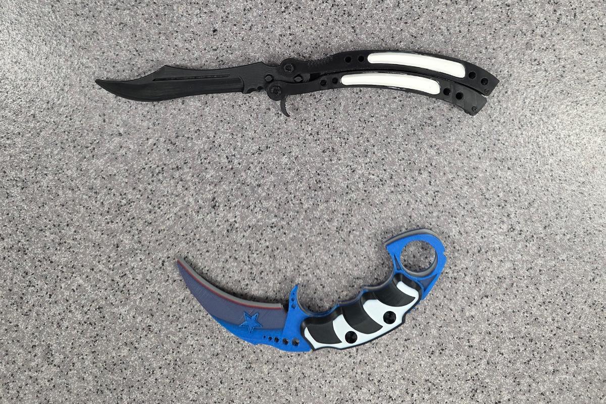 Kuva kahdesta muovisesta 3D tulostimella tulostetusta veitsestä. Toinen veitsistä on suori ja musta/valkoinen, toinen veitsi on käyrä ja se on väriltään sininen. Veitsen kahva on musta/valkoinen.