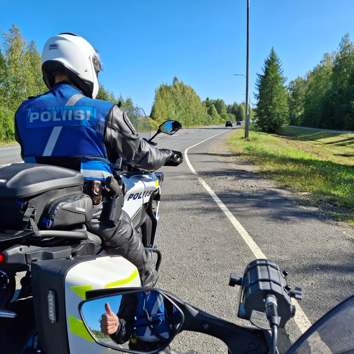 Kuvassa on kaksi poliisimoottoripyörää ja toinen poliiseista näyttää peukaloa taustapeilissä.