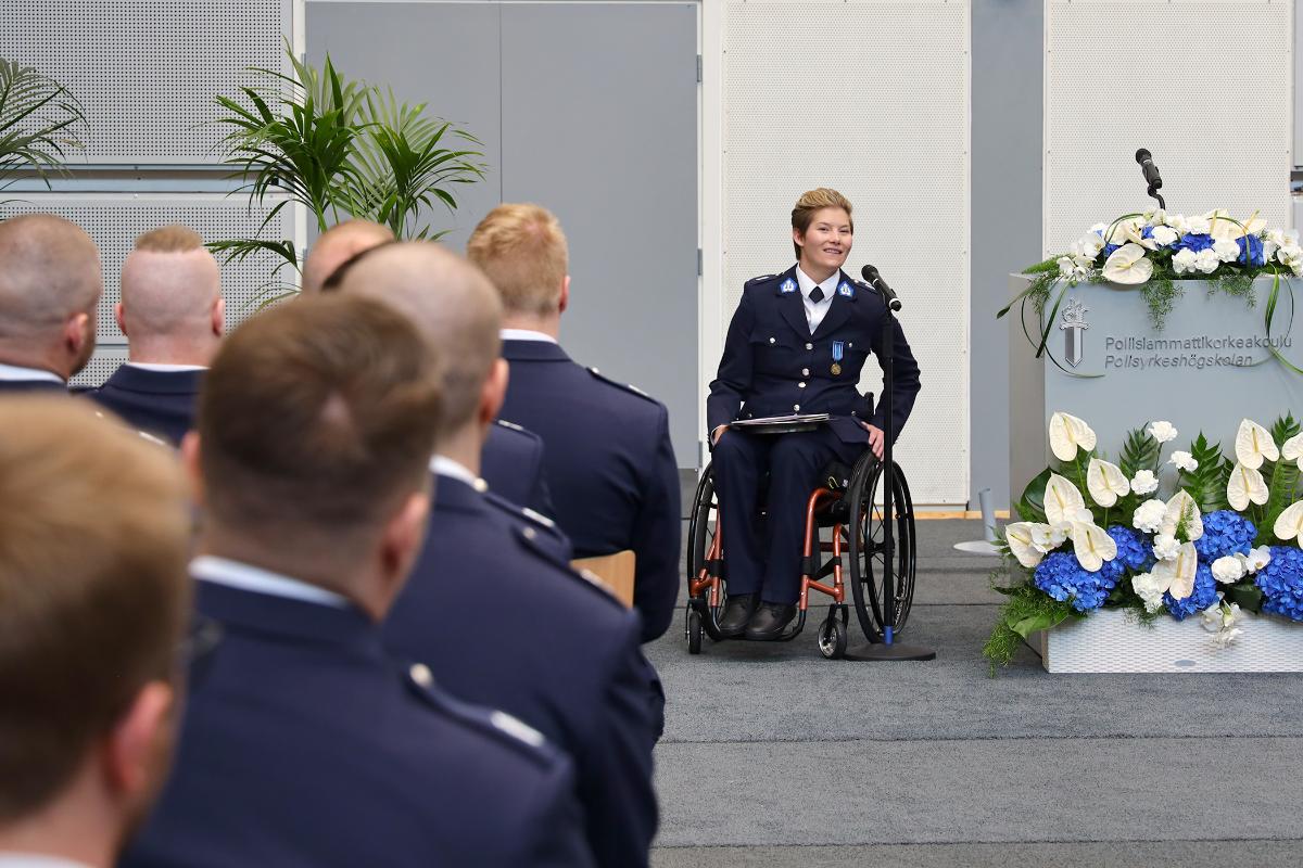 Valan antanut poliisi pitää puhetta puhujakopin vieressä juuri valmistuneille poliiseille.