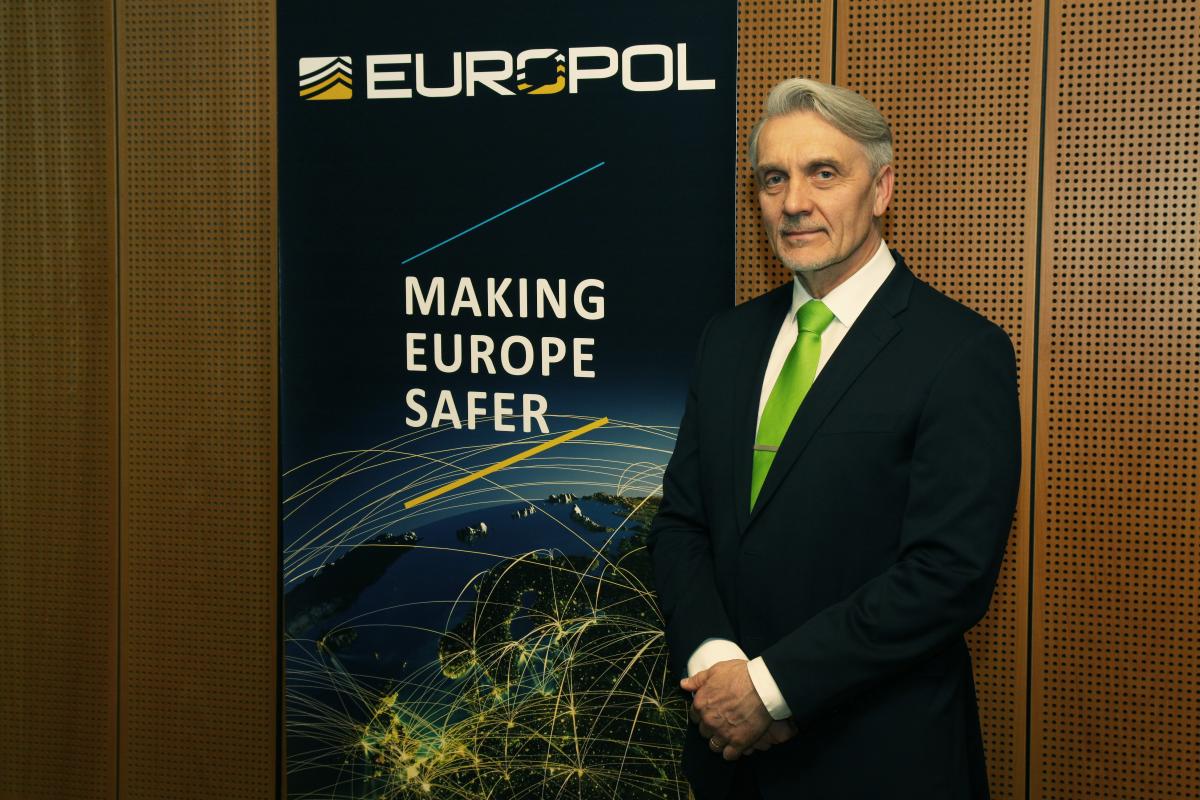 Taustakuvassa teksti Europol, making Europe safer. Kuvan vieressä seisoo mies tummassa puvussa.