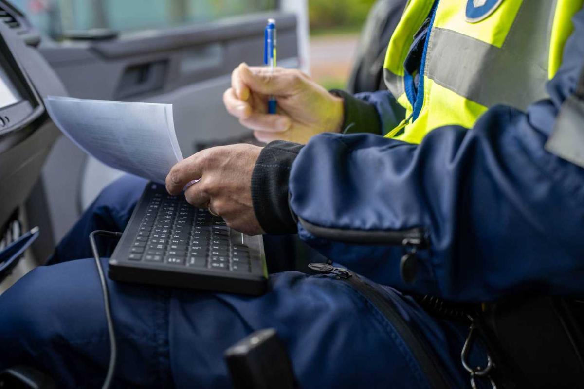 The police officer writes a ticket in the vehicle.