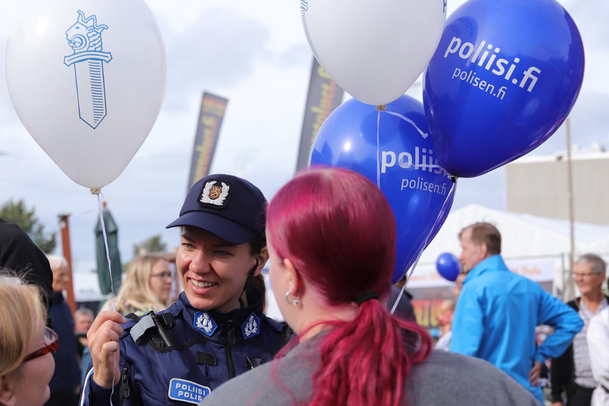Polisen pratar med medborgarna på ett utomhusevenemang och håller ballonger i händerna.