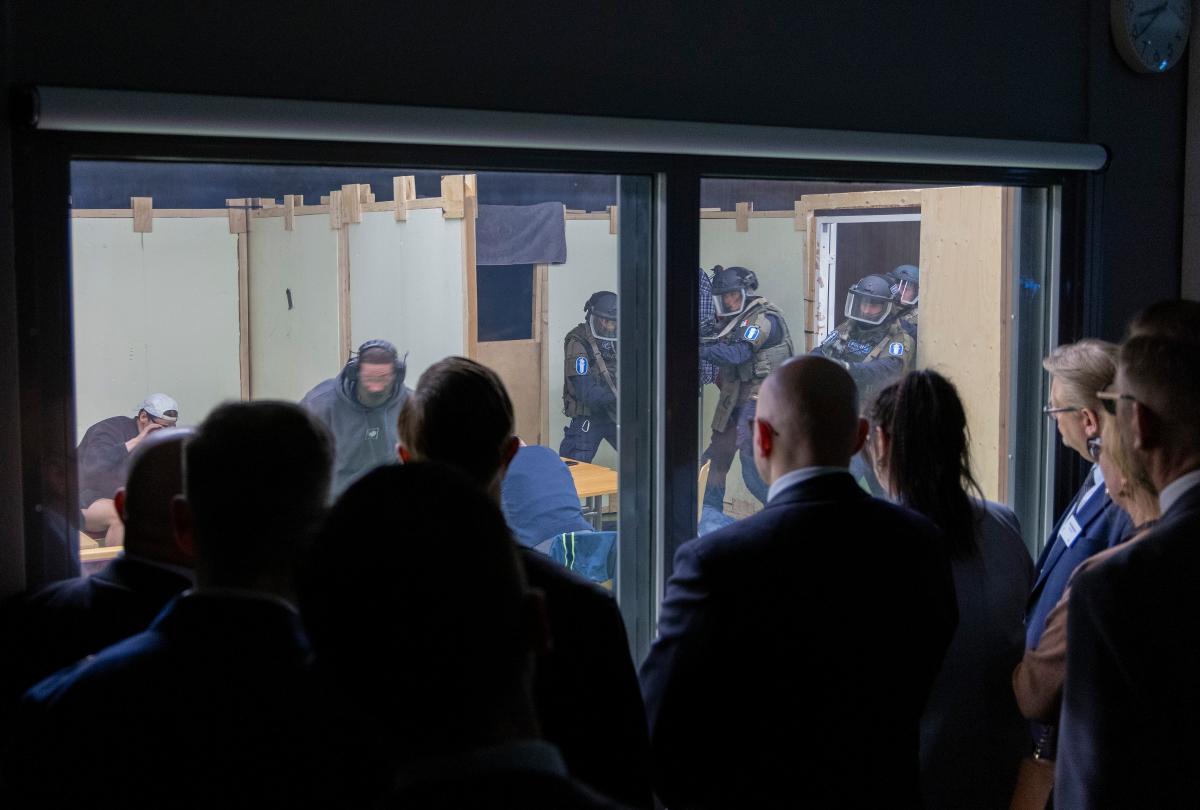 Kursdeltagarna tittar på polisens agerande i en övning från andra sidan glaset.