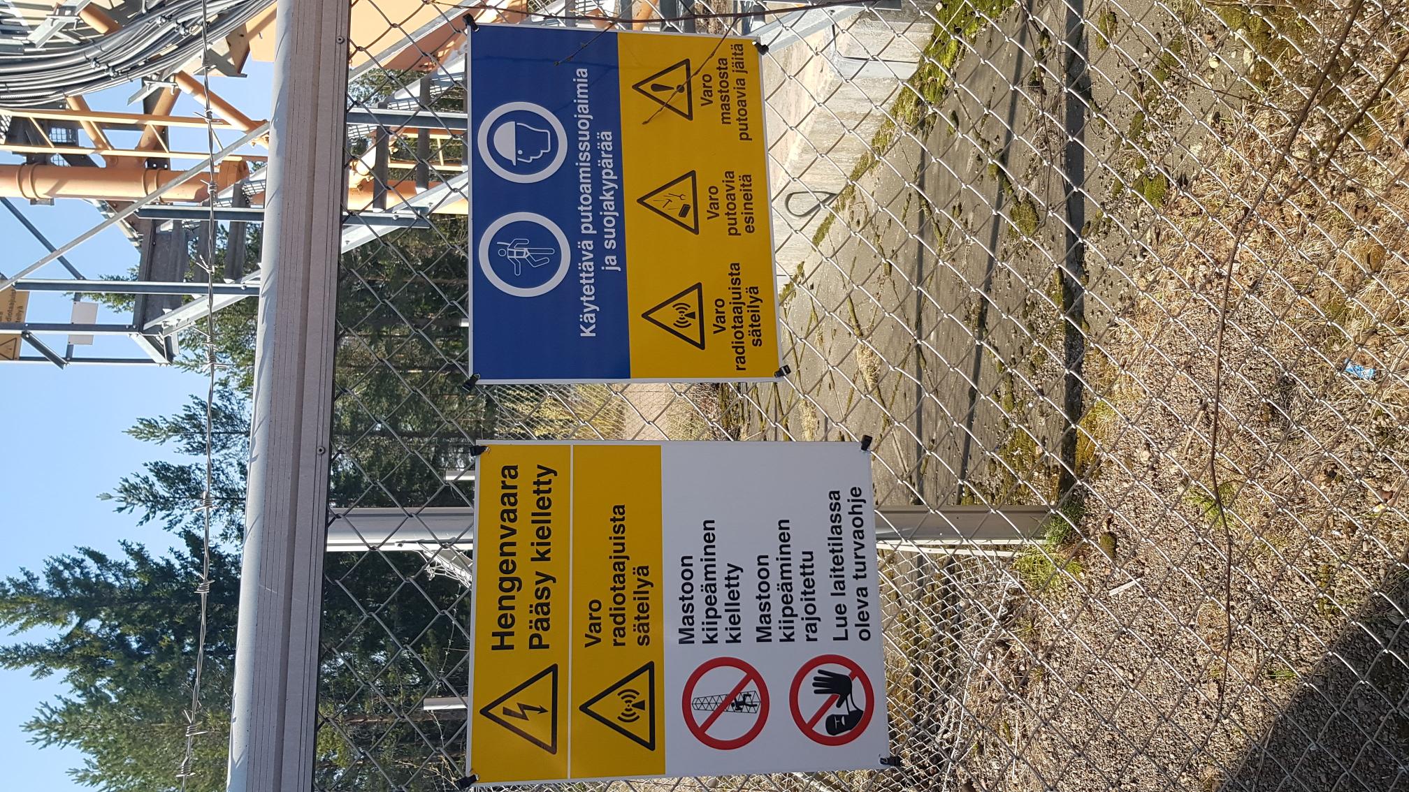 Mesh fence with warning signs such as danger to life.