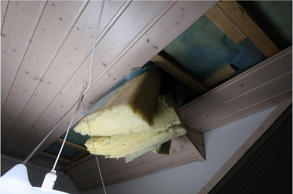 Omakotitalon rikottu sisäkatto, josta roikkuu eristevillaa.