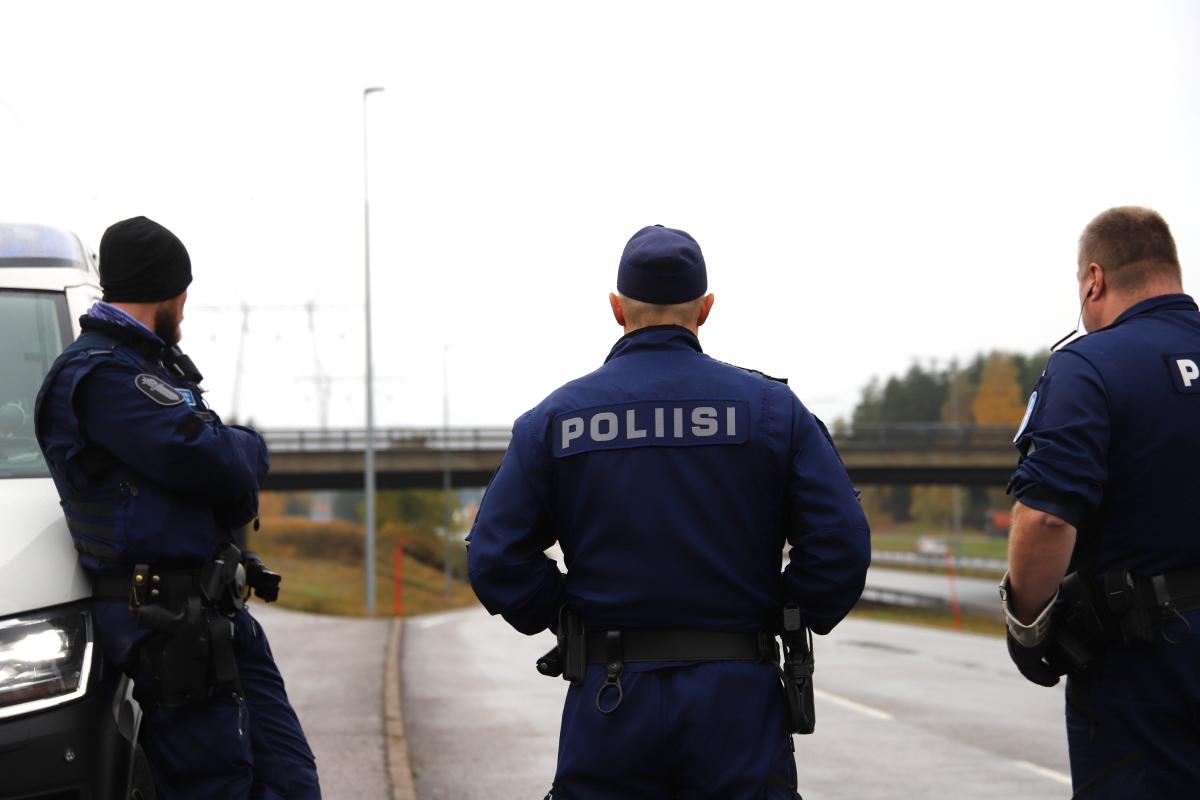 Kolme poliisia seisoo selin moottoritien laidassa katsoen tulevia ajoneuvoja.