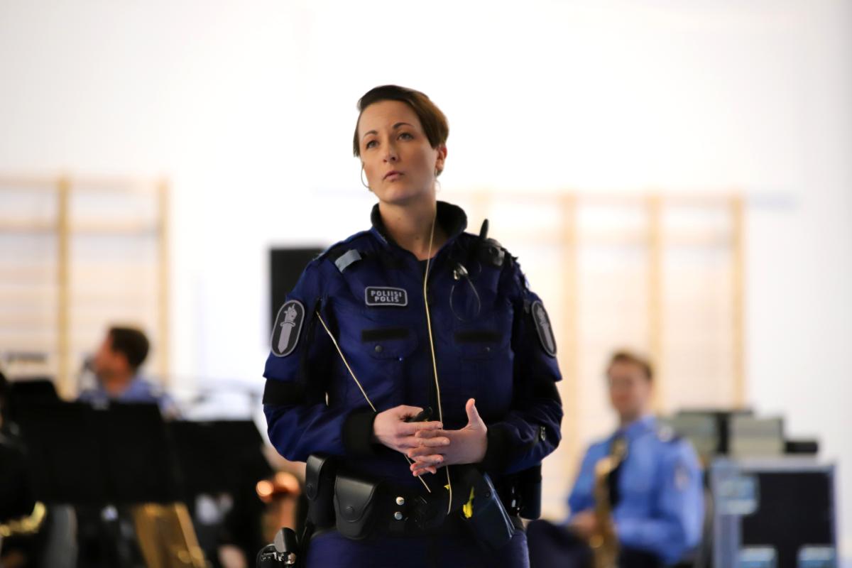 Poliisi Johanna Lindroos puhuu orkesterin edessä yleisölle.