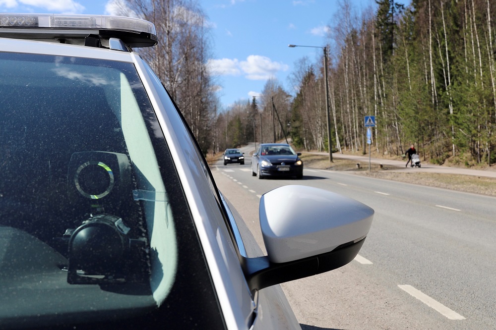 Poliisiauton etuikkunalle sijoitettu nopeusvalvontakamera kuvaa ohiajavia henkilöautoja.