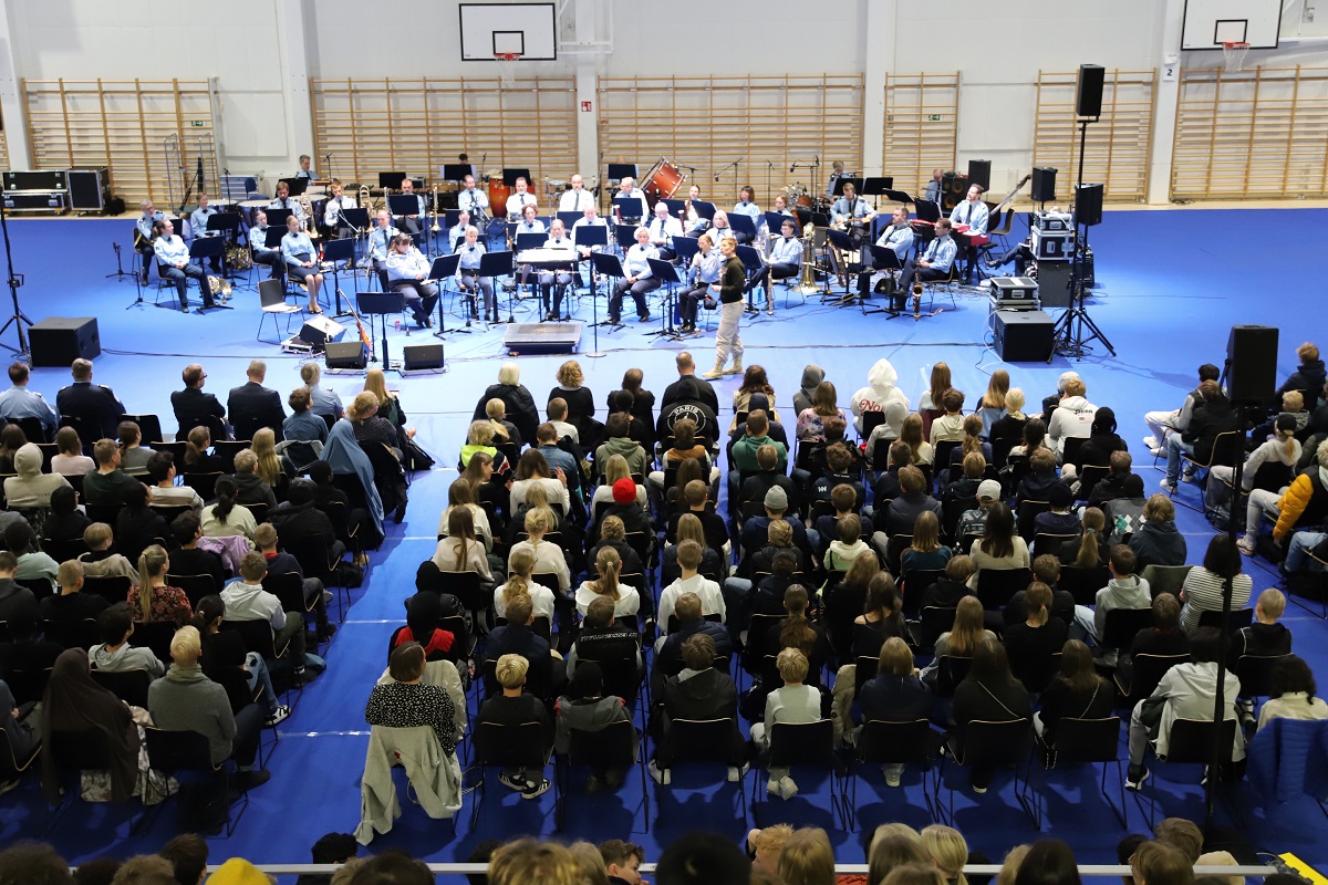 Poliisi puhuu orkesterin edessä katsomossa istuville nuorille.