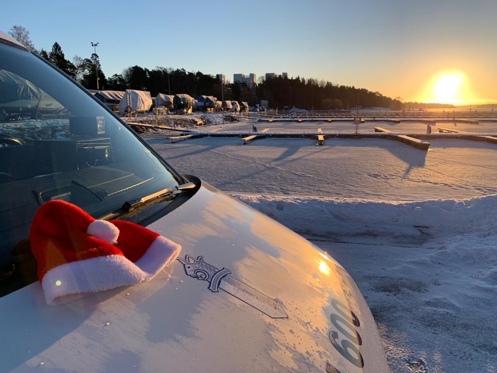 Poliisiauto auringon paisteessa tonttuhattu konepellillä.