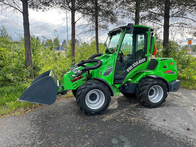 Vihreä Avant-kuormaaja on pysäköitynä puiden eteen. 