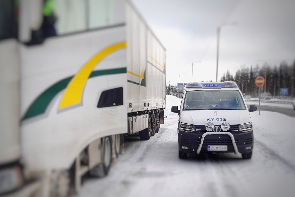 Poliisiauto ja rekka-auto seisovat vierekkäin valtatien varrella olevalla pysähdyspaikalla, poliisi seisoo rekka-auton ovella.