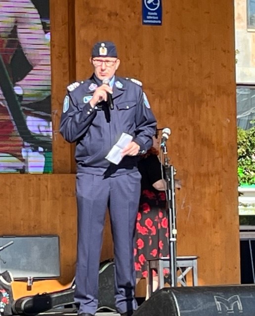 Poliisipäällikkö Samppa Holopainen puhumassa mikrofonikädessä Joensuun torilavalla.