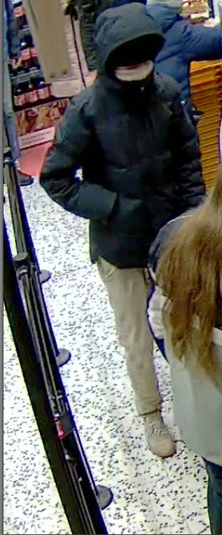 Valvontakameran kuva kaupan kassalta tummaan takkiin puketunueesta ryöstäjästä