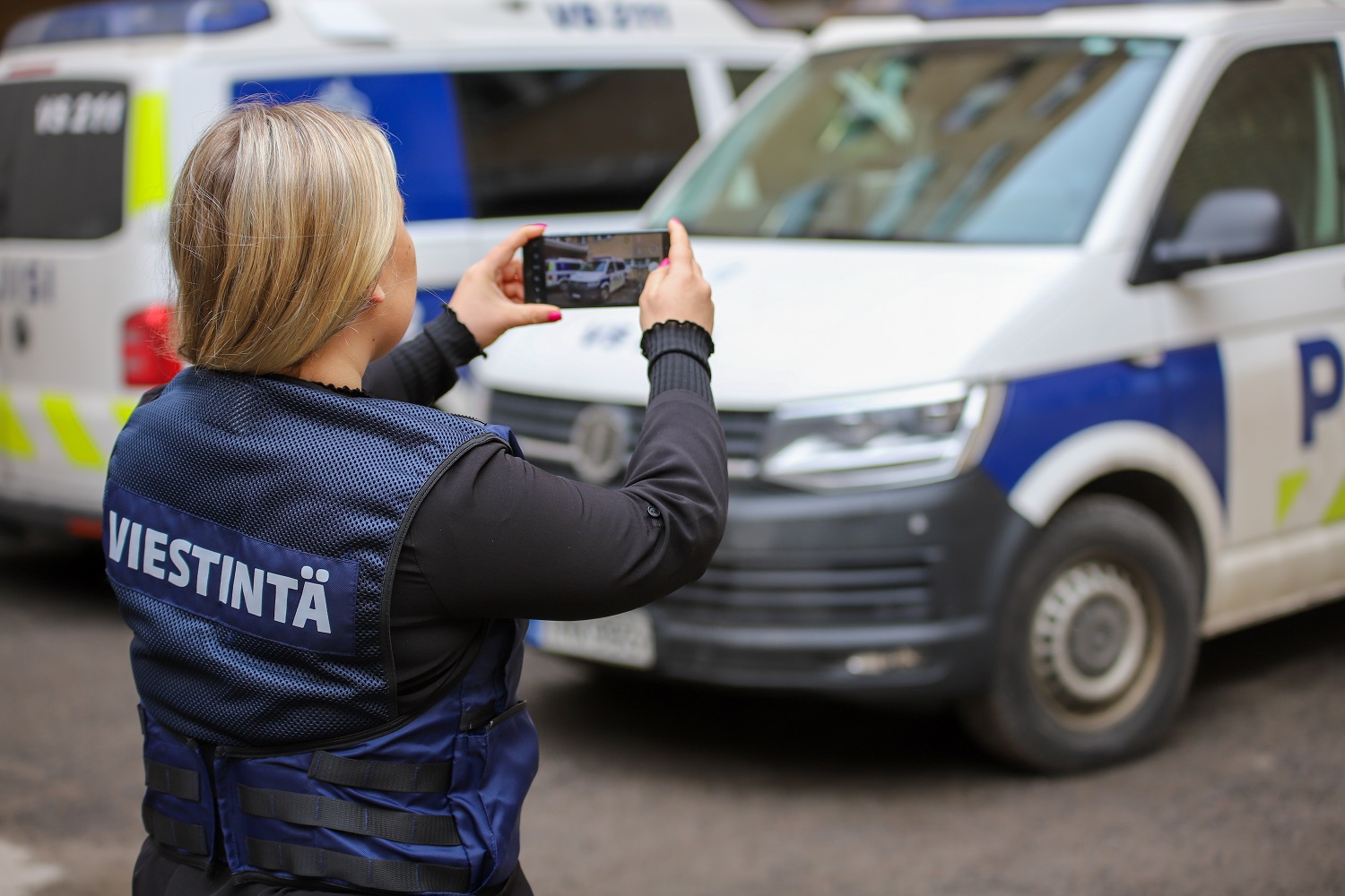 Poliisin viestintäasiantuntija ottaa valokuvan poliisiautosta.