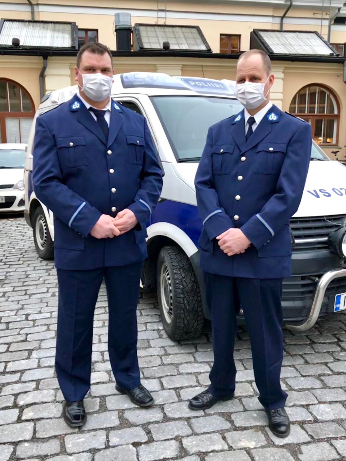 Två poliser står framför en polisbil.