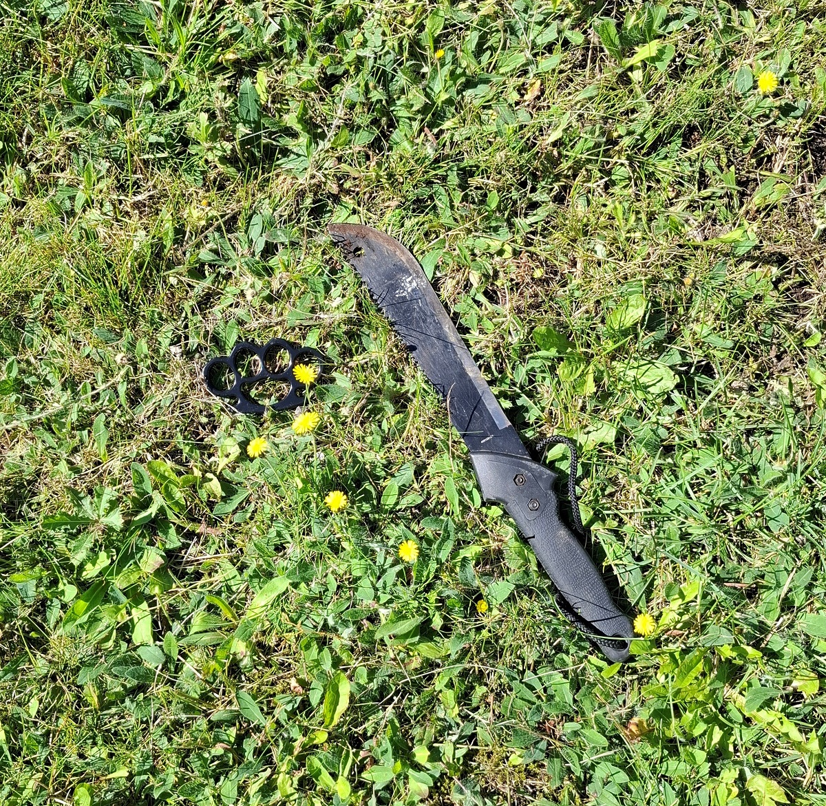 Nurmikolle aseteltu musta veitsi ja nyrkkirauta.