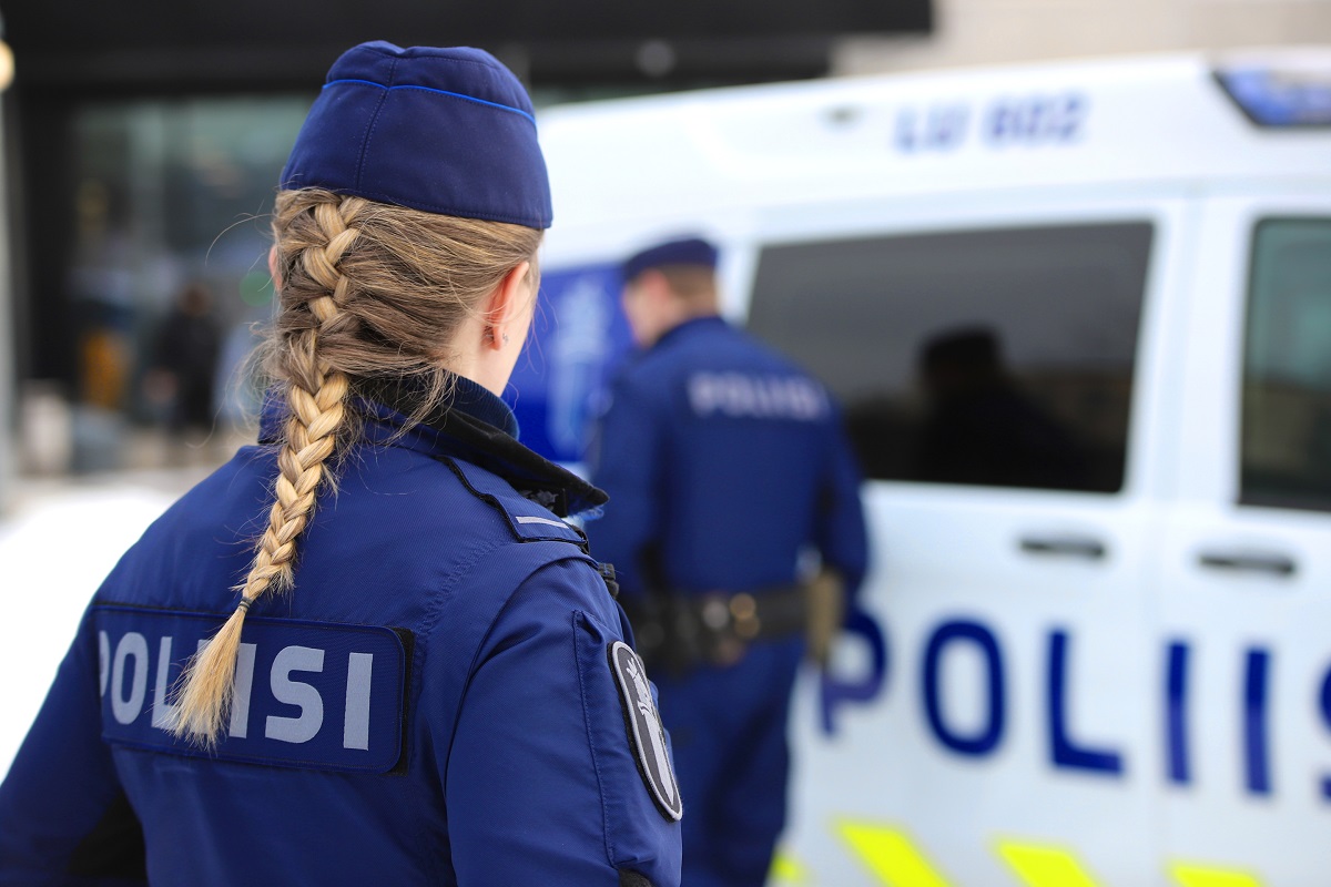 Naispoliisi katsoo kohti poliisiauton edessä liikkuvaa miespoliisia.