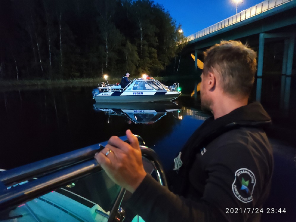 Kaksi venettä vesillä iltahämärässä. Toinen poliisin vene ja toisessa veneessä erätarkastaja.
