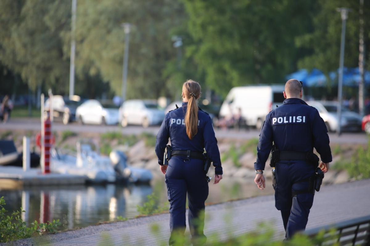 Kaksi poliisia kävelee tiellä rannalla