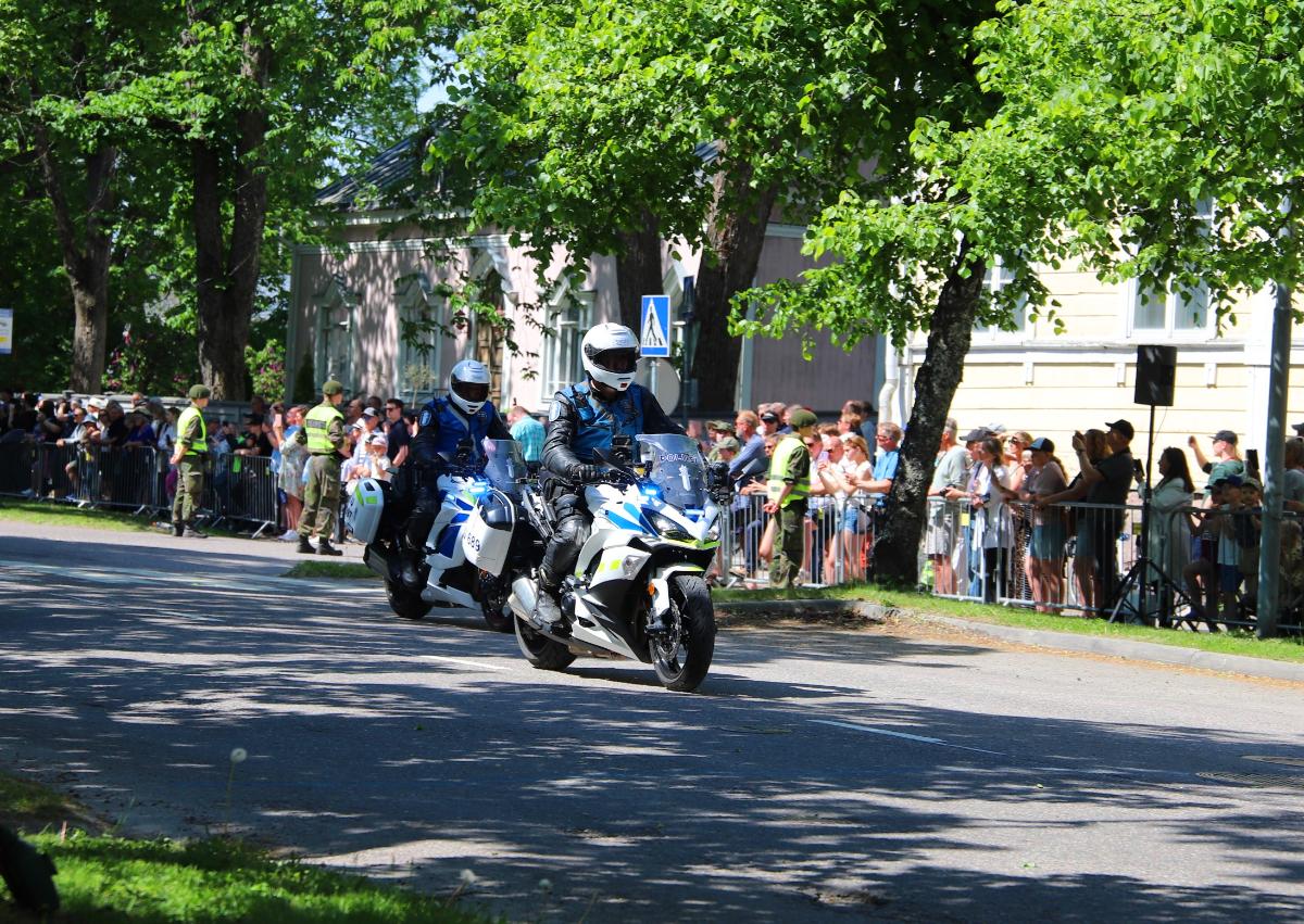 Moottoripyöräpoliisit vetävät paraatia, jota on seuraamassa paljon ihmisiä.