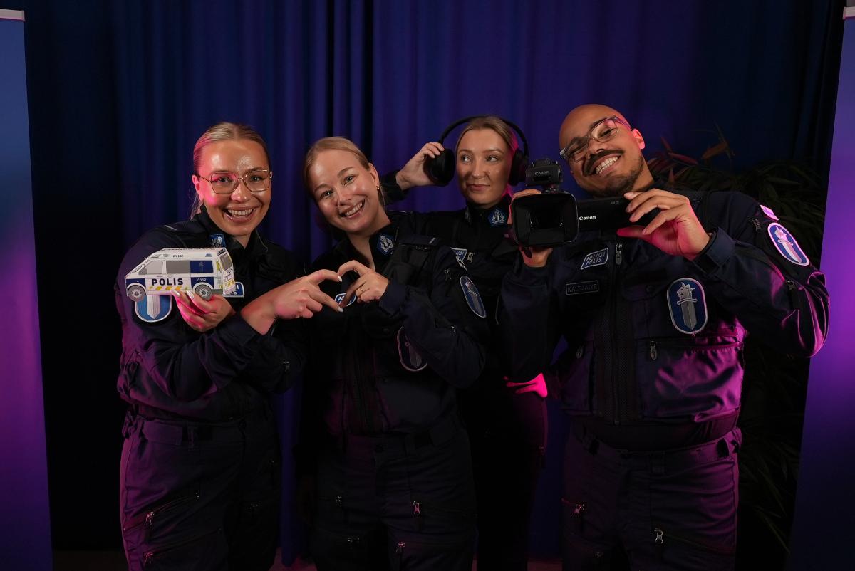 Neljä konstaapelia seisoo rivissä iloisina.