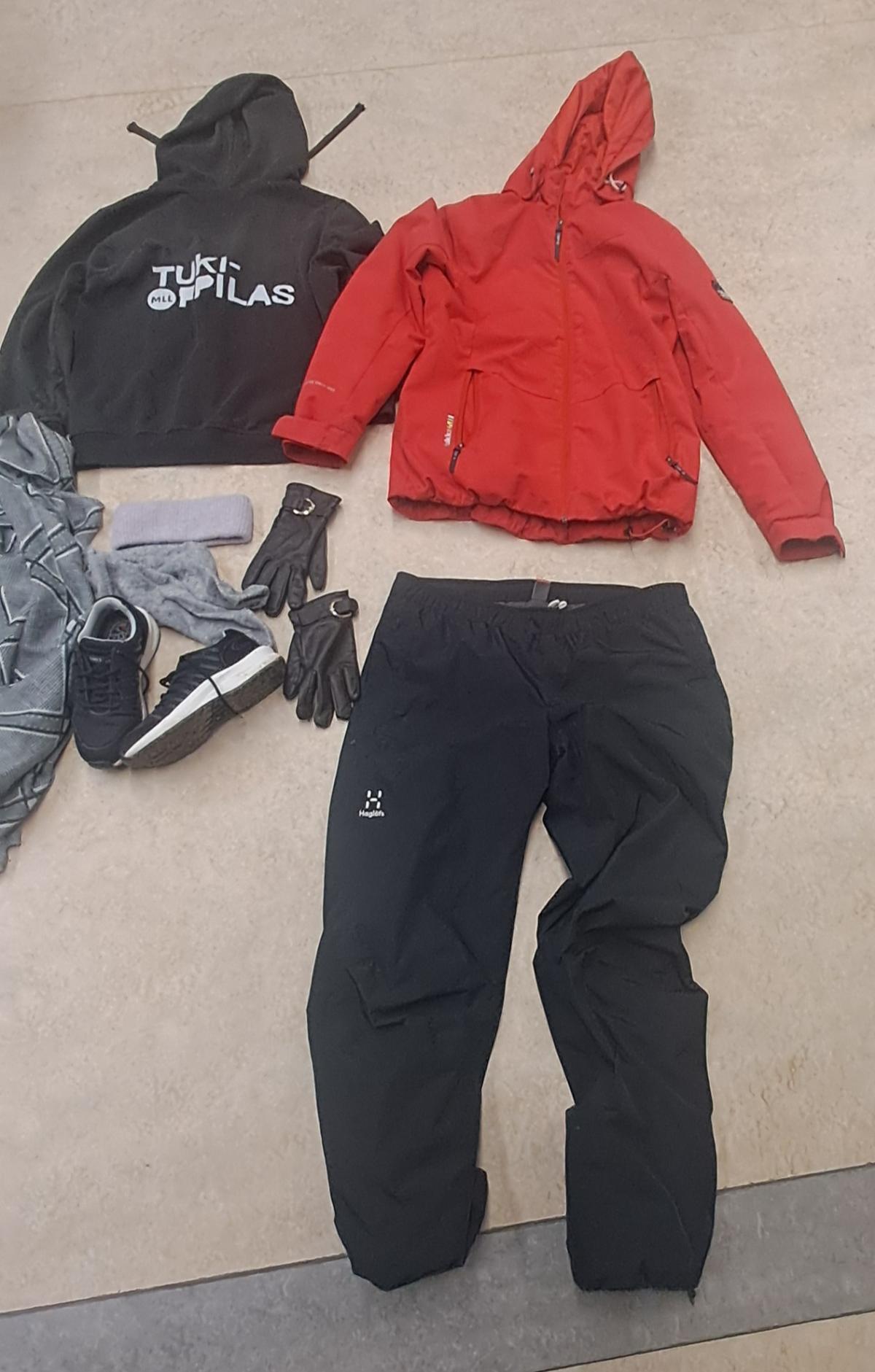 Musta huppari (selässä teksti tukioppilas), punainen takki, mustat ulkoiluhousut, mustat lenkkitossut, ruskeat sormikkaat.