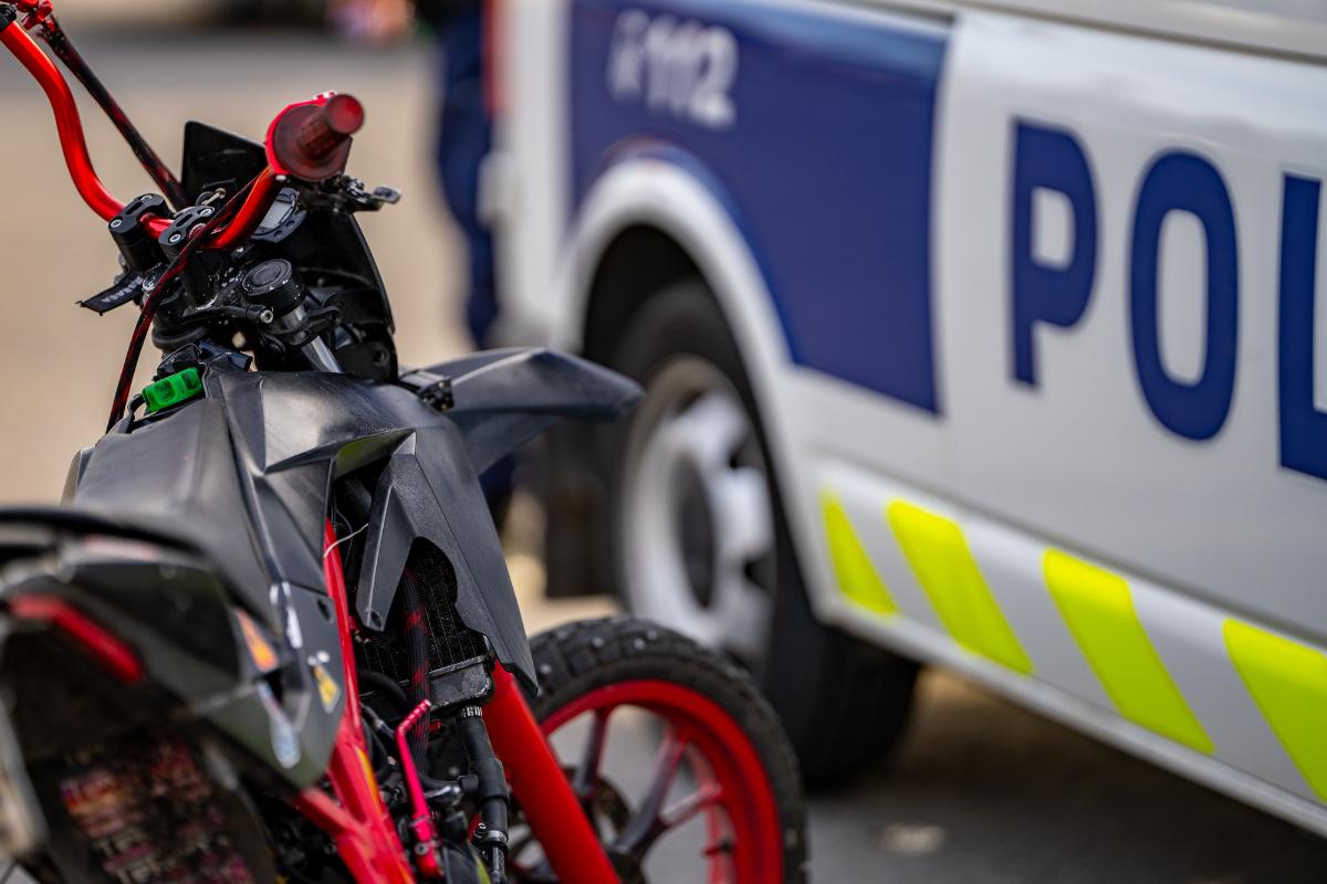 Mopo, jonka taustalla näkyy osa poliisiautosta.