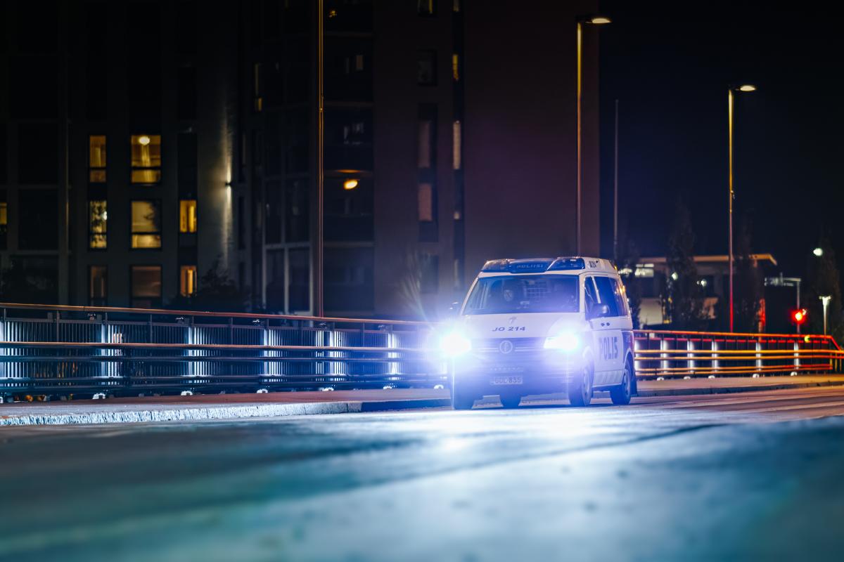 Poliisiauto valaistussa kaupungissa pimeän aikaan.